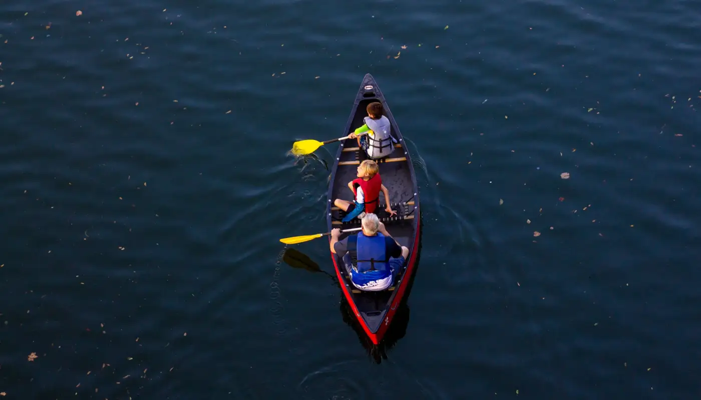Grands-parents et petits-enfants faisant du canoë sur un lac calme