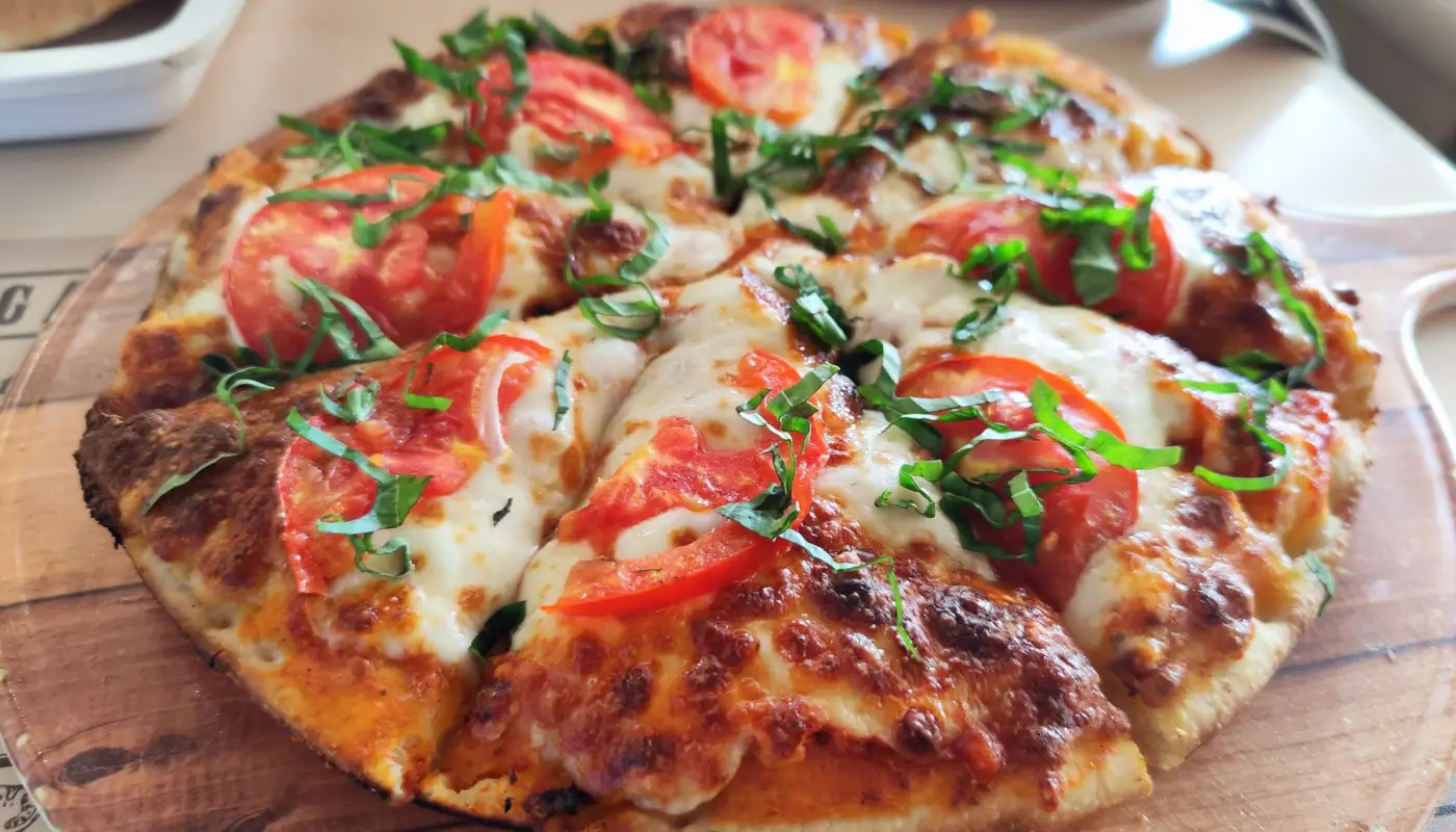 Pizza margherita fraîchement sortie du four, avec tomate, mozzarella et basilic